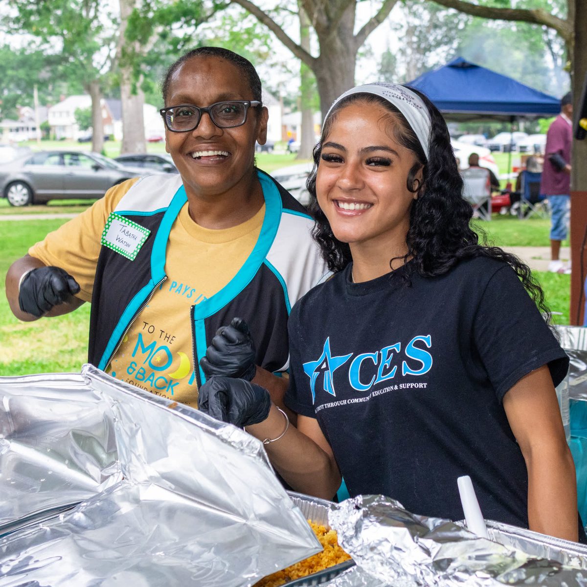 Two volunteers smiling behind the serving table
