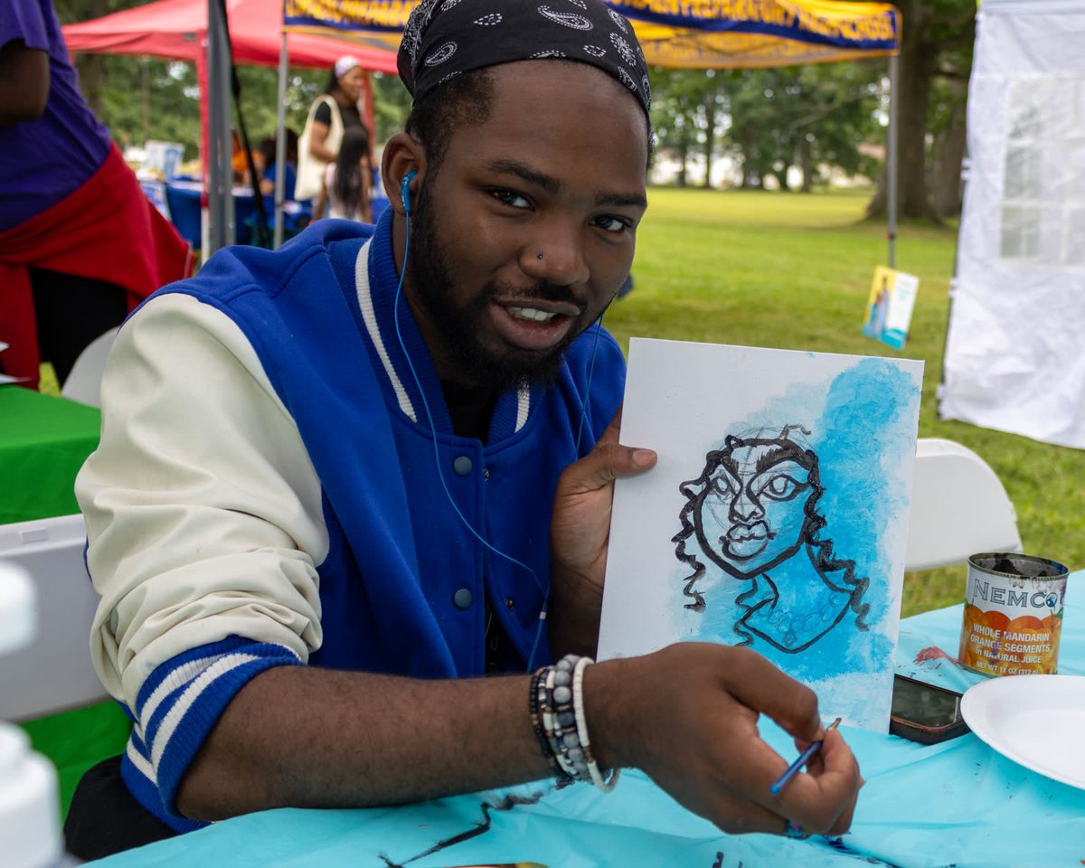 Man in a blue jacket holding up his finished portrait