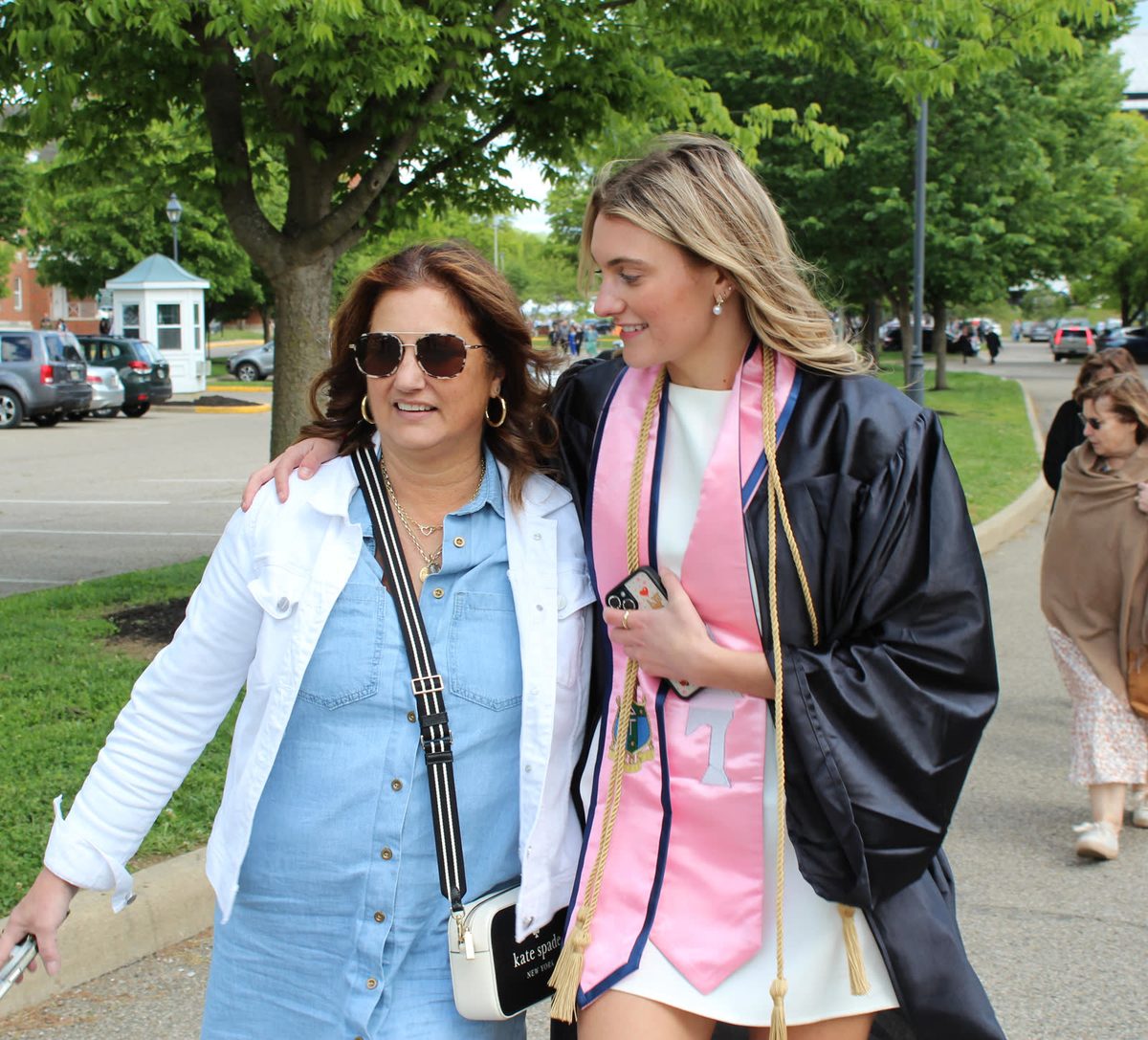 Graduate in cap and gown walking with her mom after commencement