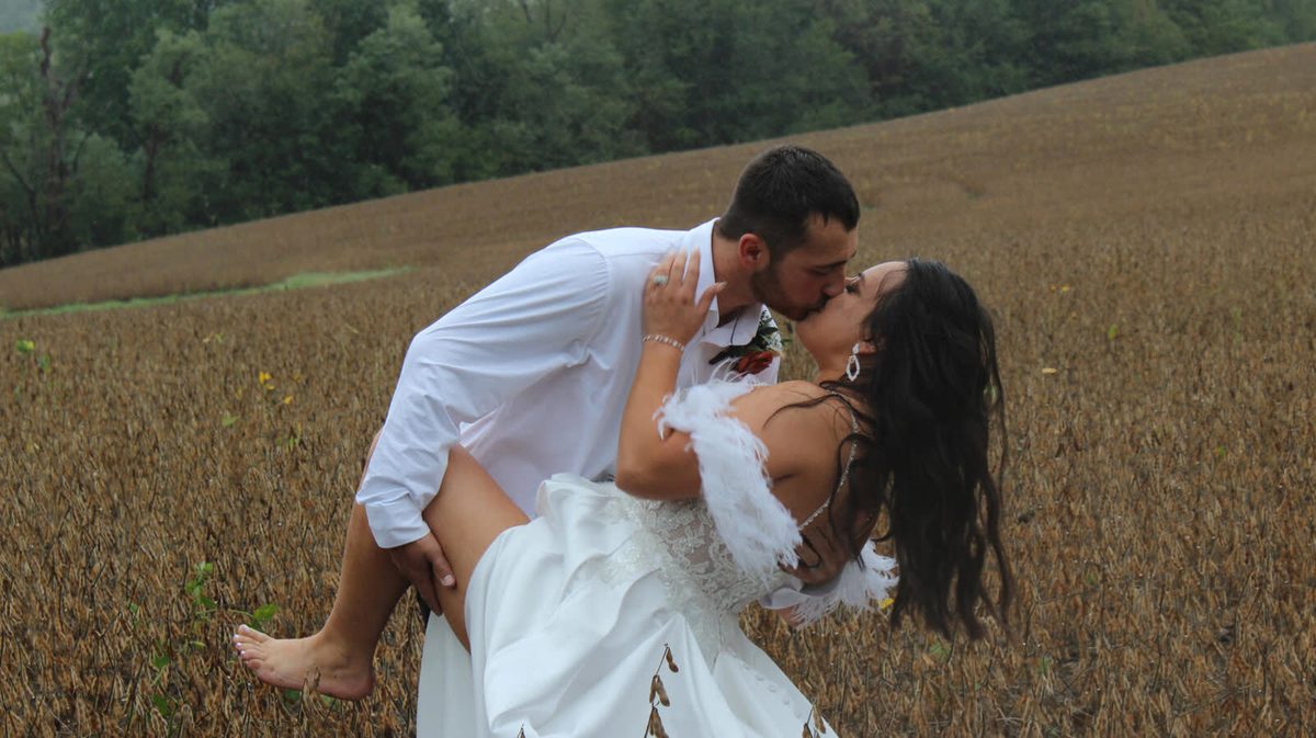 Groom dipping the bride for a kiss in a wheat field
