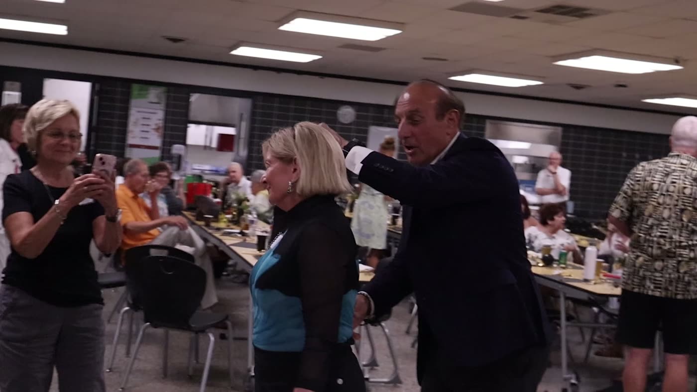 Guests greeting each other at a community dinner covered by JS Media